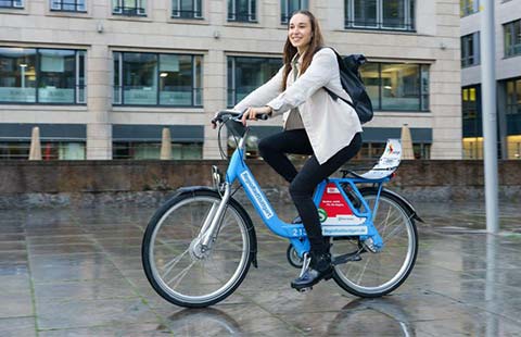 Eine Frau fährt in einem urbanen Gebiet auf einem blauen RegioRad Bikesharing Fahrrad.