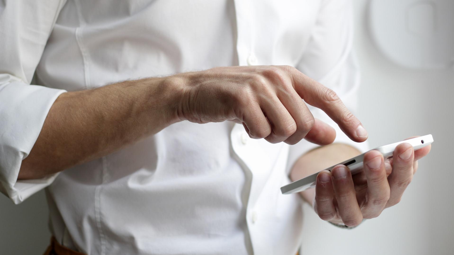 Eine Hand tippt auf einem Smartphone.