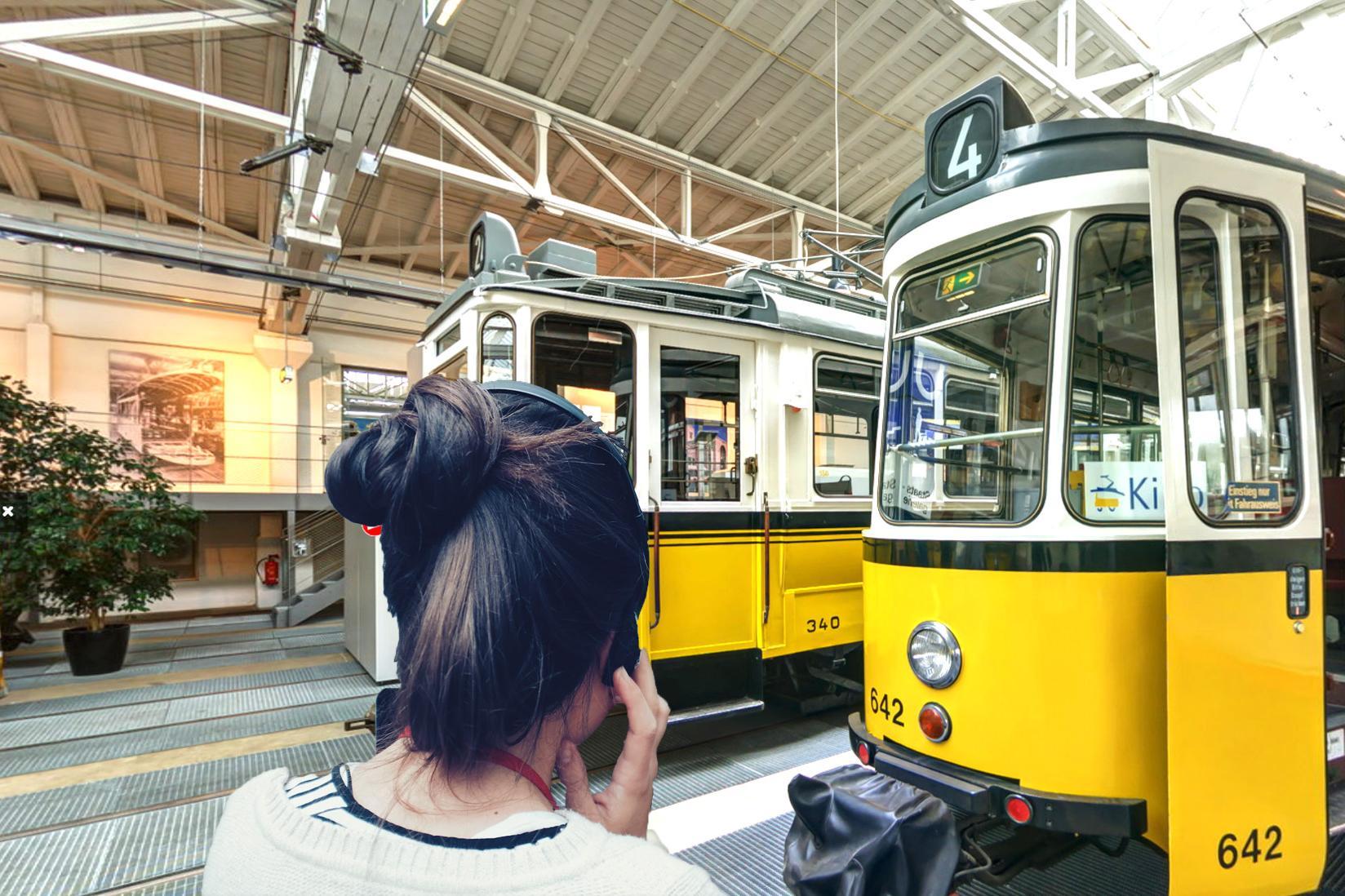 Eine Frau mit Kopfhörern schaut eine Straßenbahn.
