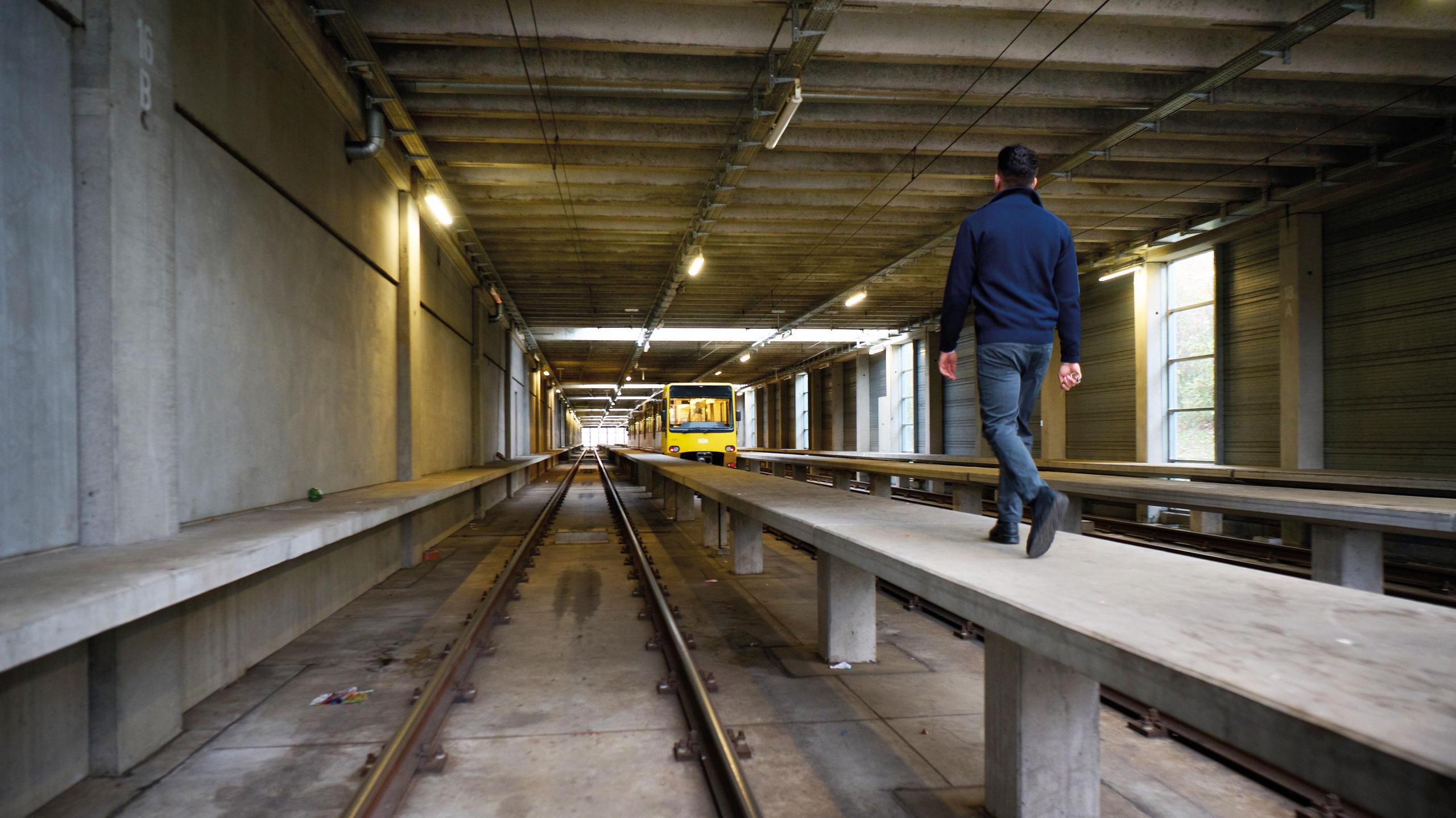 Ein Mann geht in einem Stadtbahnbetriebshof entlang des Bahnsteigs.