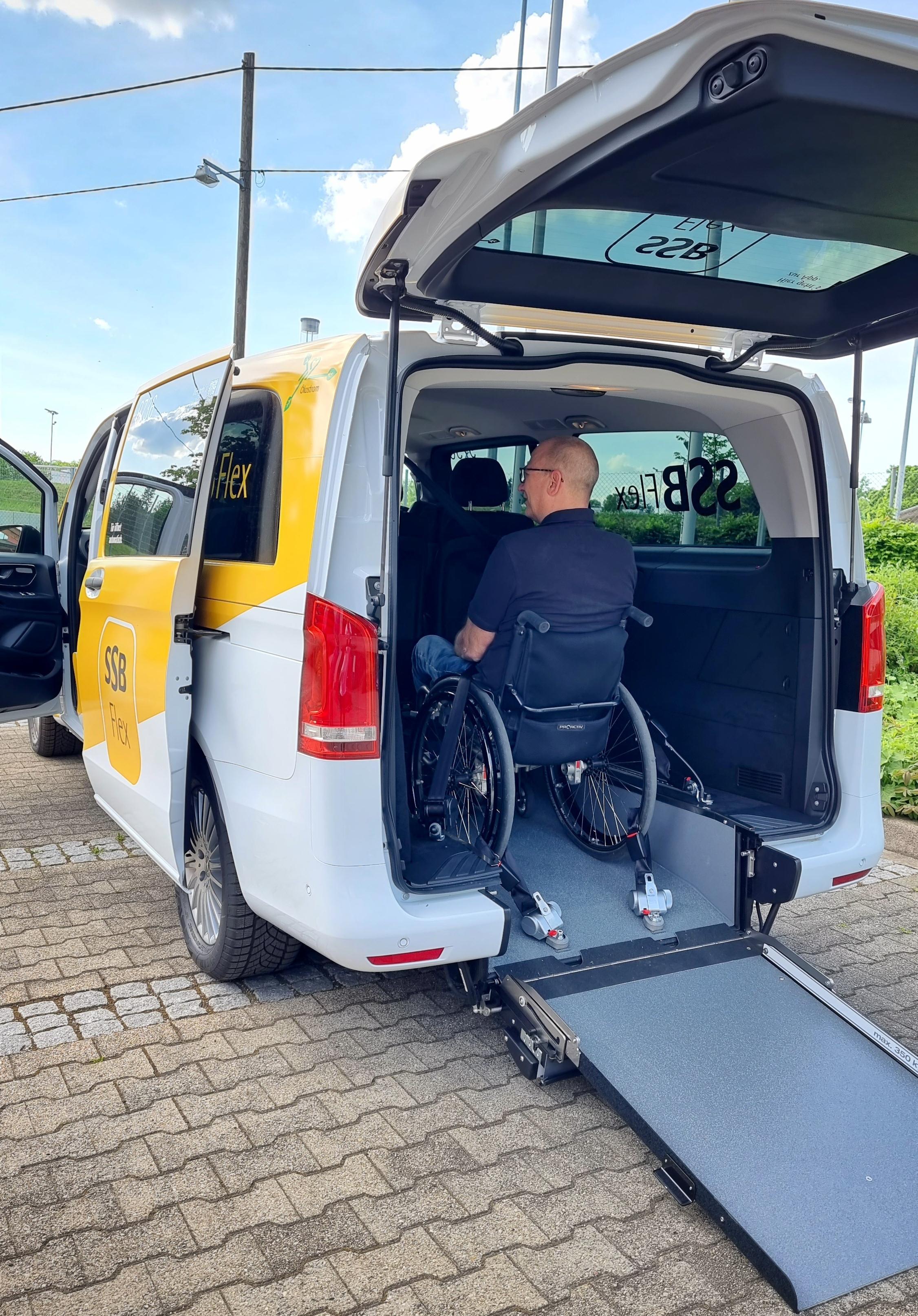 Foto: Ein Rollstuhlfahrer sitzt im hinteren Bereich des SSB Flex Fahrzeugs. Die Heckklappe ist geöffnet, die Rampe ist ausgelegt.