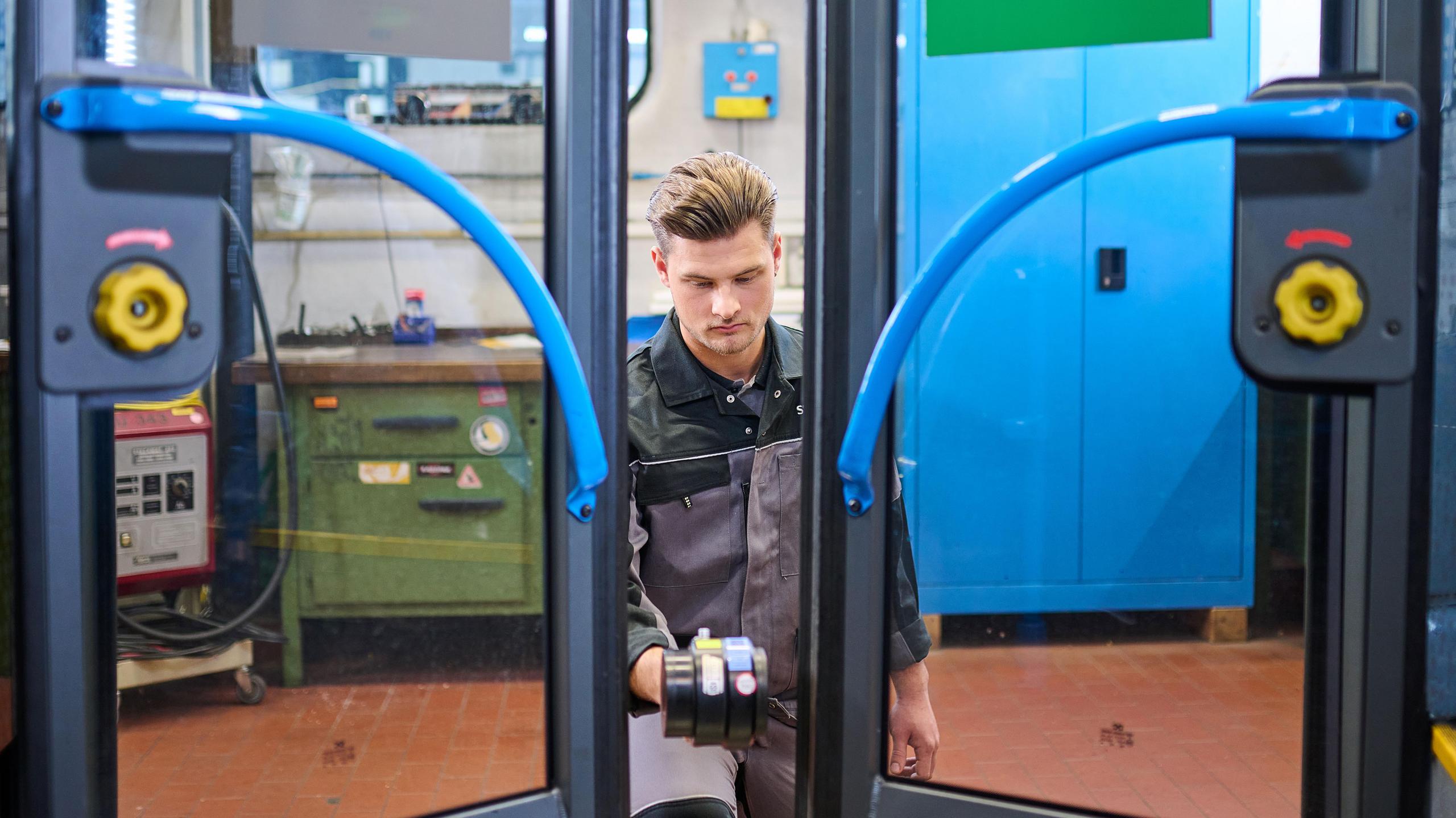 Ein Mitarbeiter prüft die Türen eines Busses.