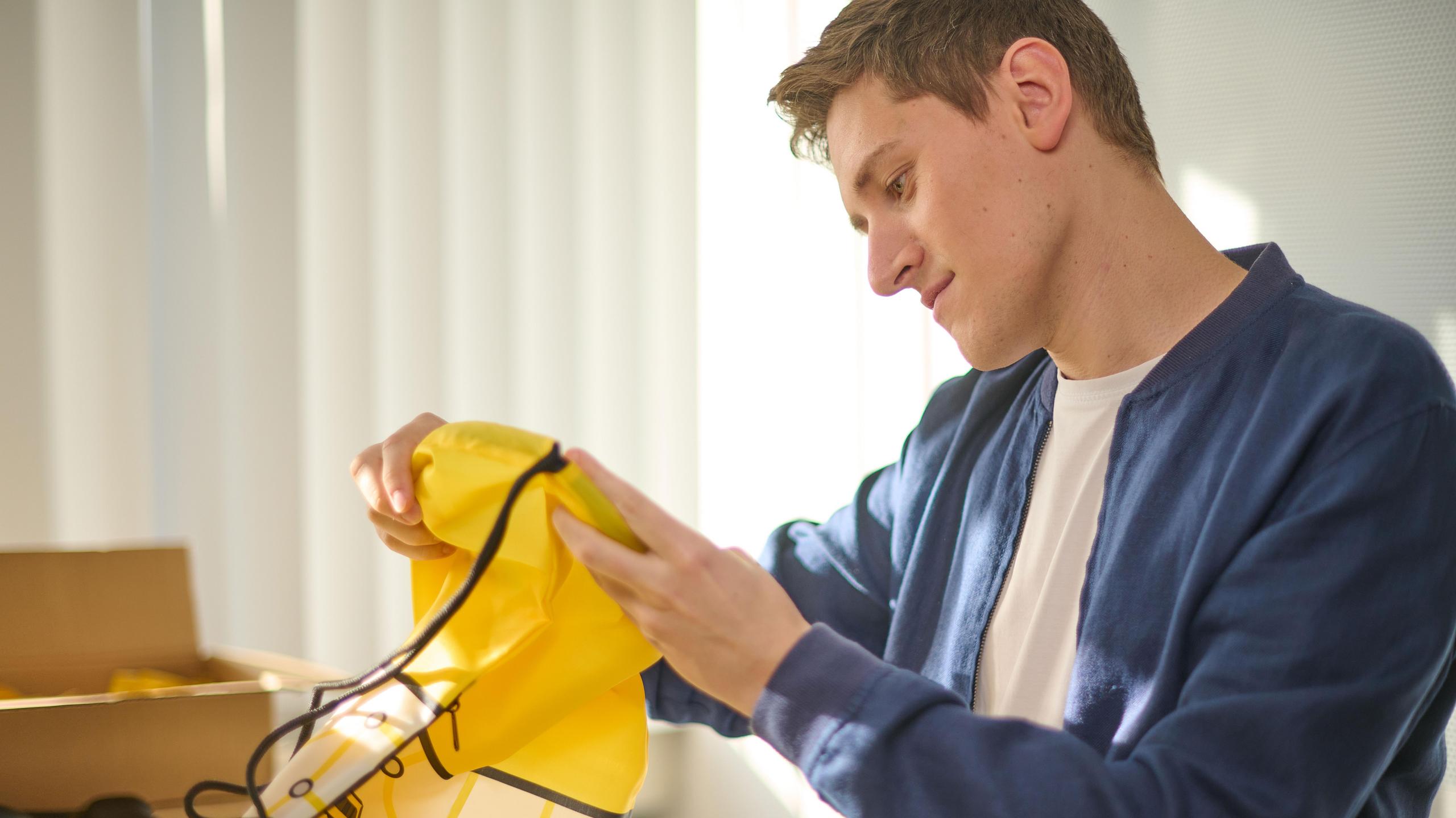 Ein Auszubildender prüft die Qualität einer Tragetasche.