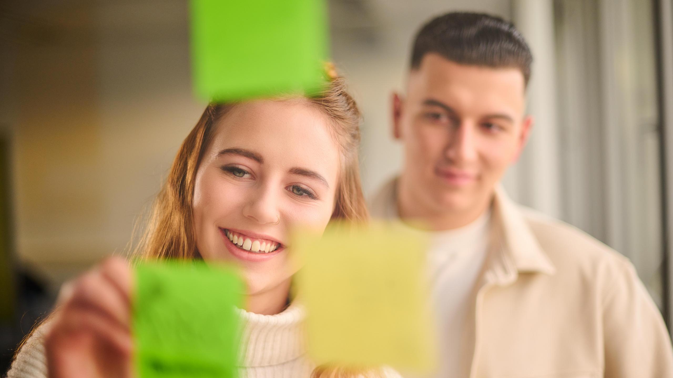 Zwei junge Menschen beschriften einen Notizzettel.