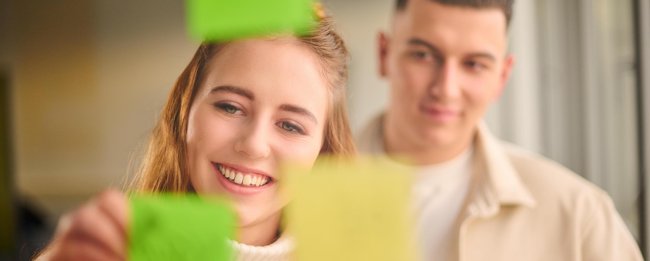 Zwei junge Menschen beschriften einen Notizzettel.