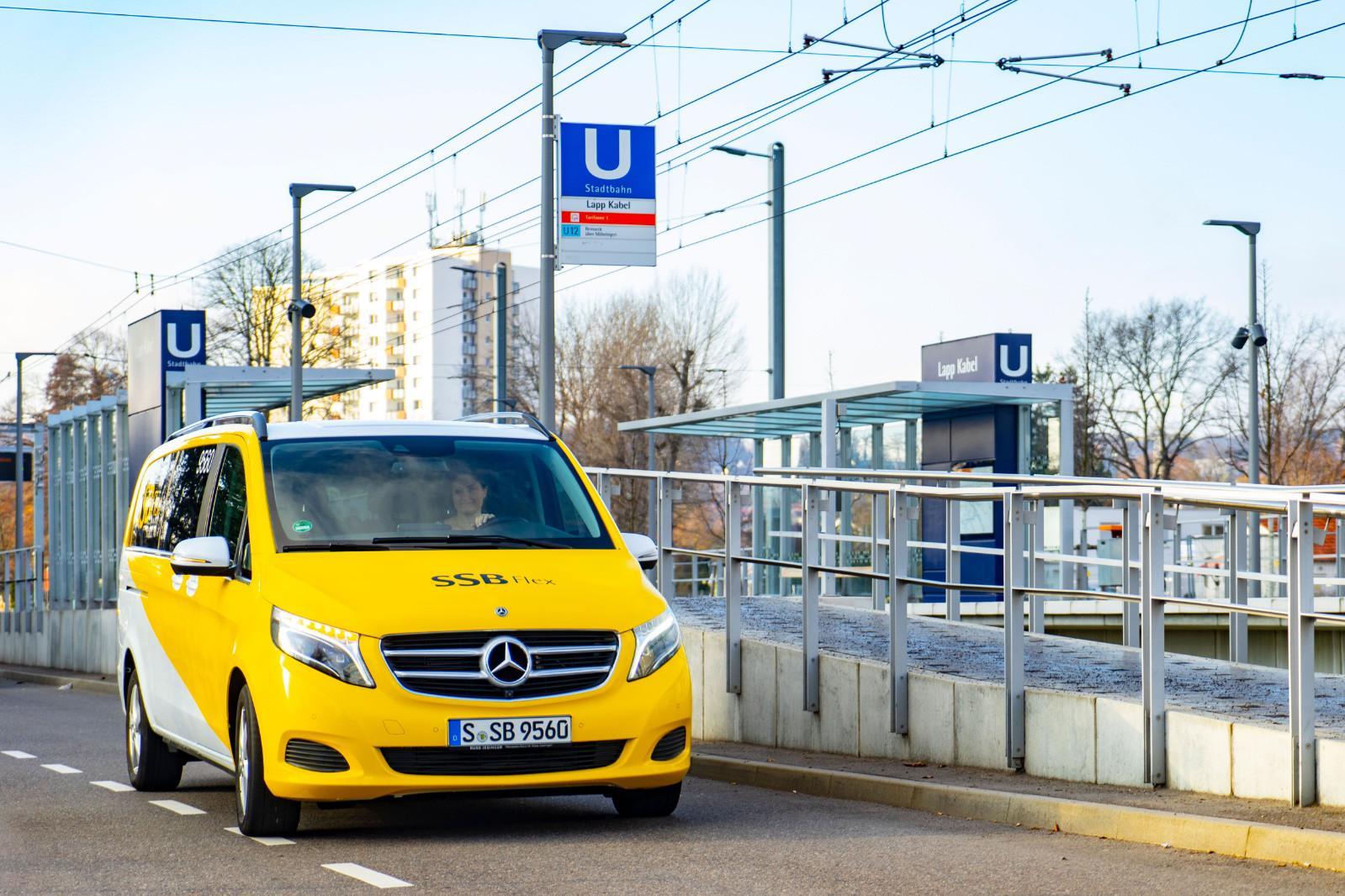 Ein SSB-Flex-Fahrzeug fährt auf der Straße an einer Stadtbahnhaltestelle vorbei.