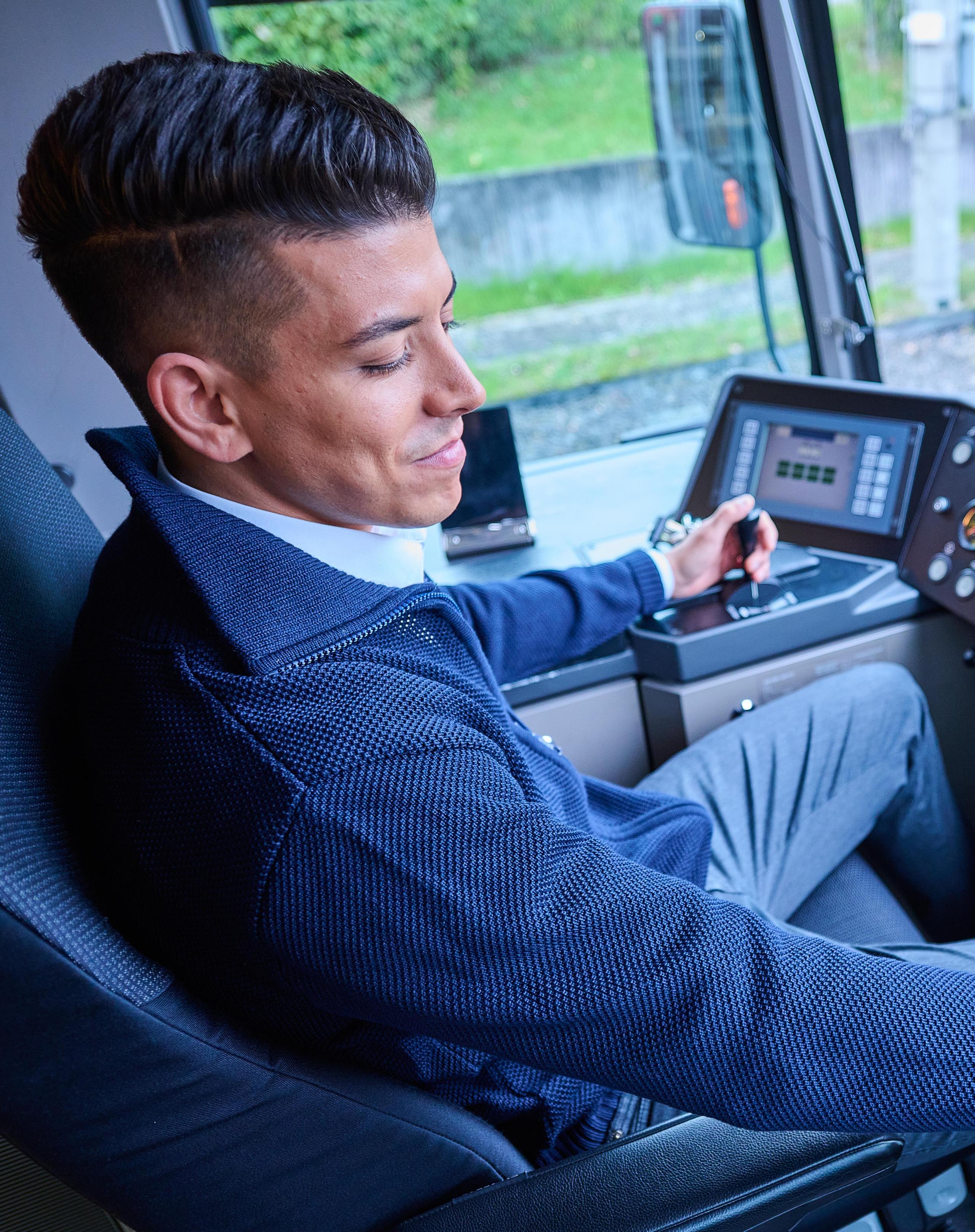 Ein Stadtbahnfahrer sitzt im Fahrerstand einer Stadtbahn und drückt einen Knopf.