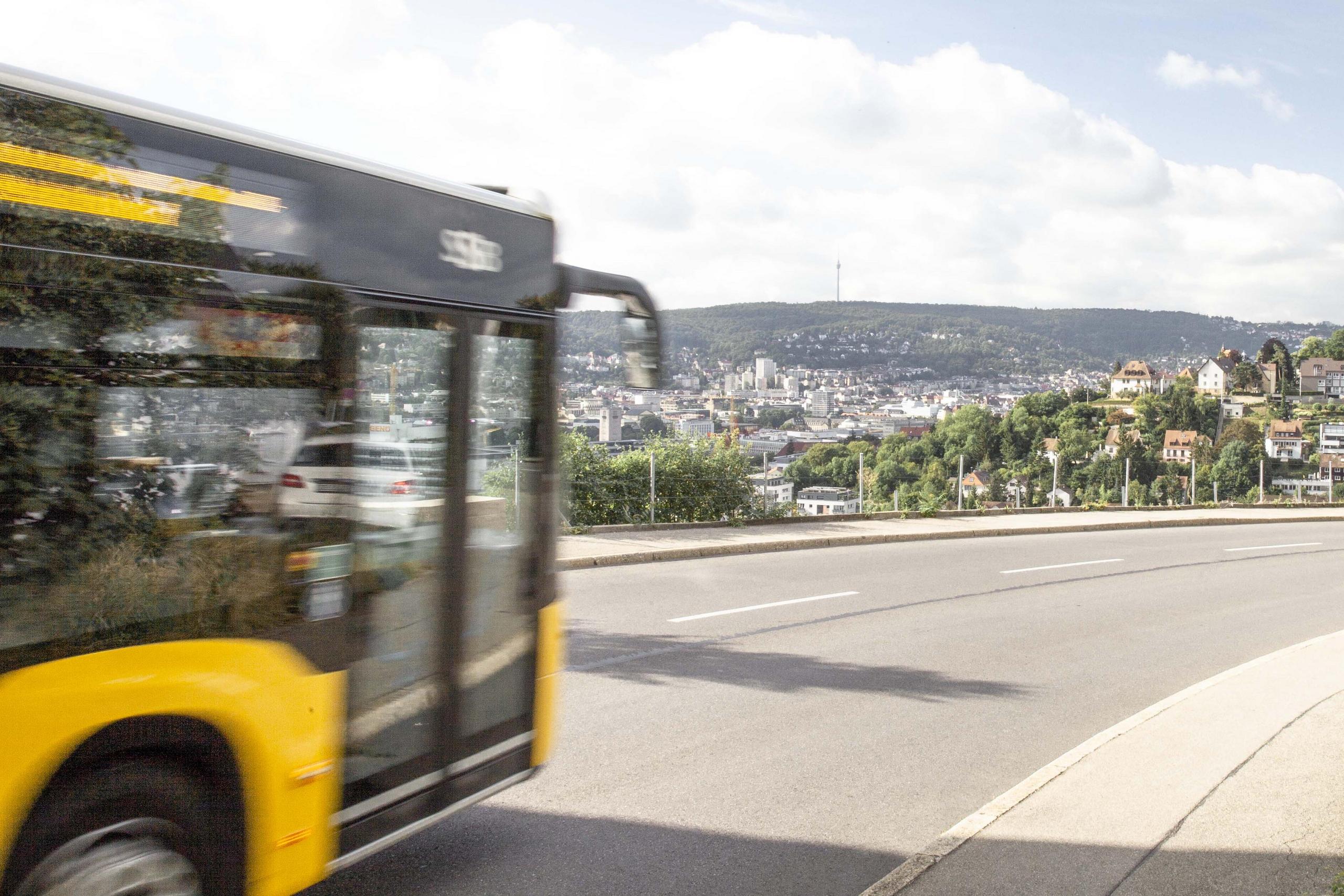 Ein Bus fährt entlang der Straße, am Horizont ist der Stuttgarter Fernsehturm.