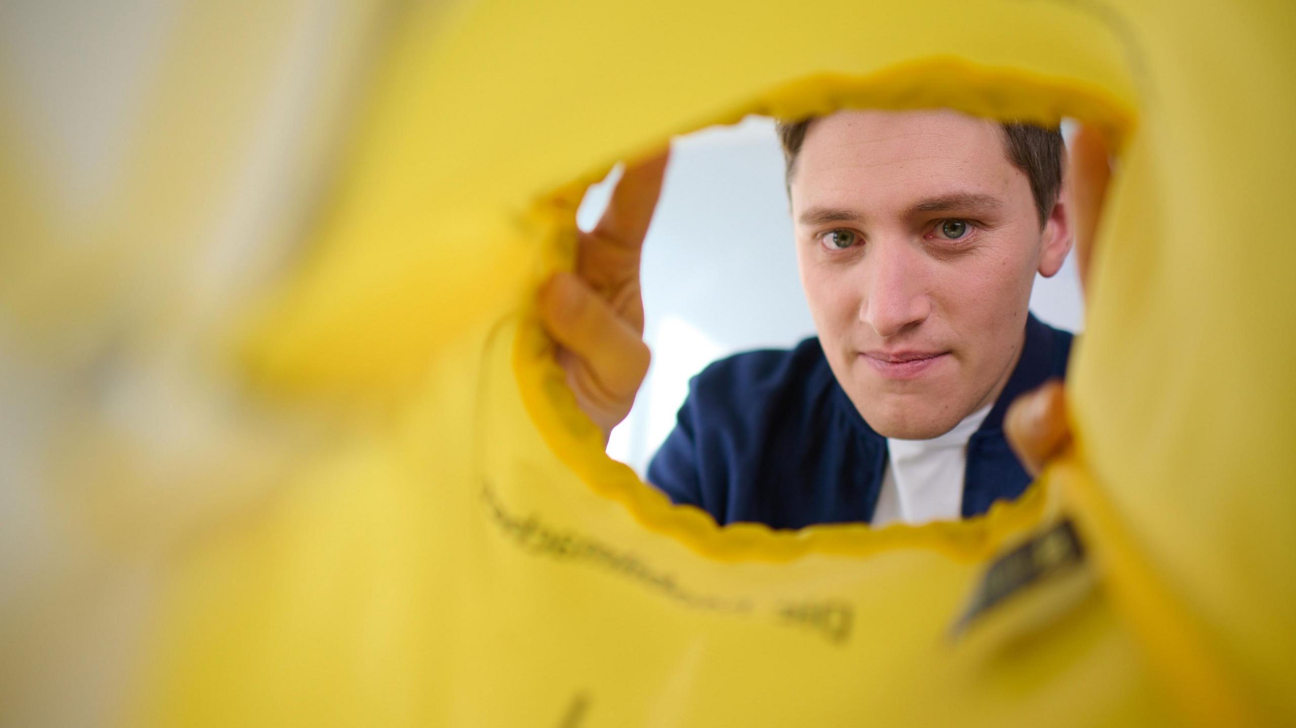 Ein junger Mann schaut lächelnd in eine Tasche.
