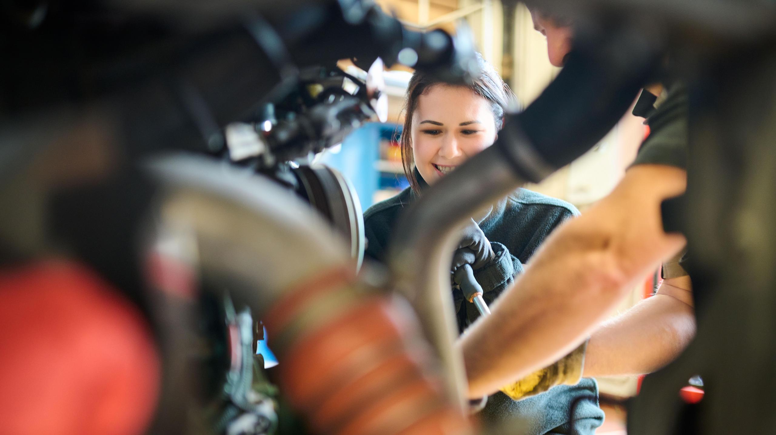 Eine Werkstattmitarbeiterin repariert einen Bus.