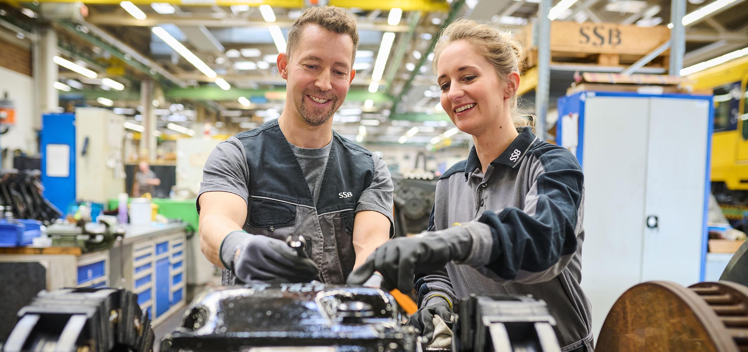 Ein Mitarbeiter zeigt einer Auszubildenden ein Stadtbahnfahrgestell.