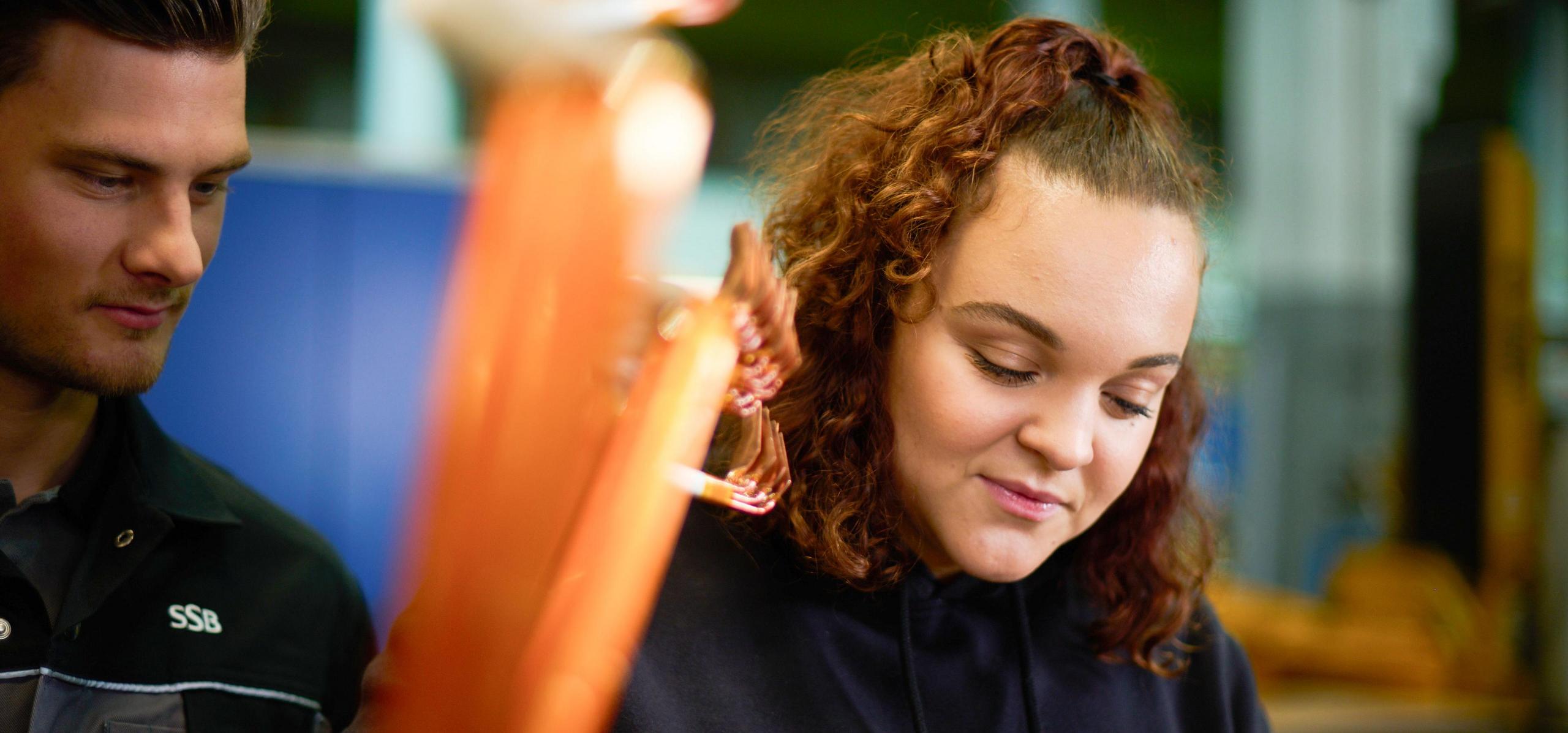 Zwei Auszubildende prüfen in der Werkstatt einen Elektromotor.