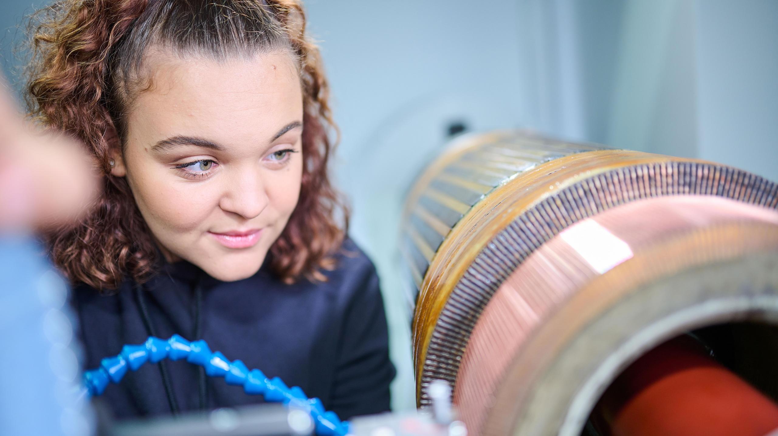 Eine Auszubildende schaut auf einen Elektromotor.