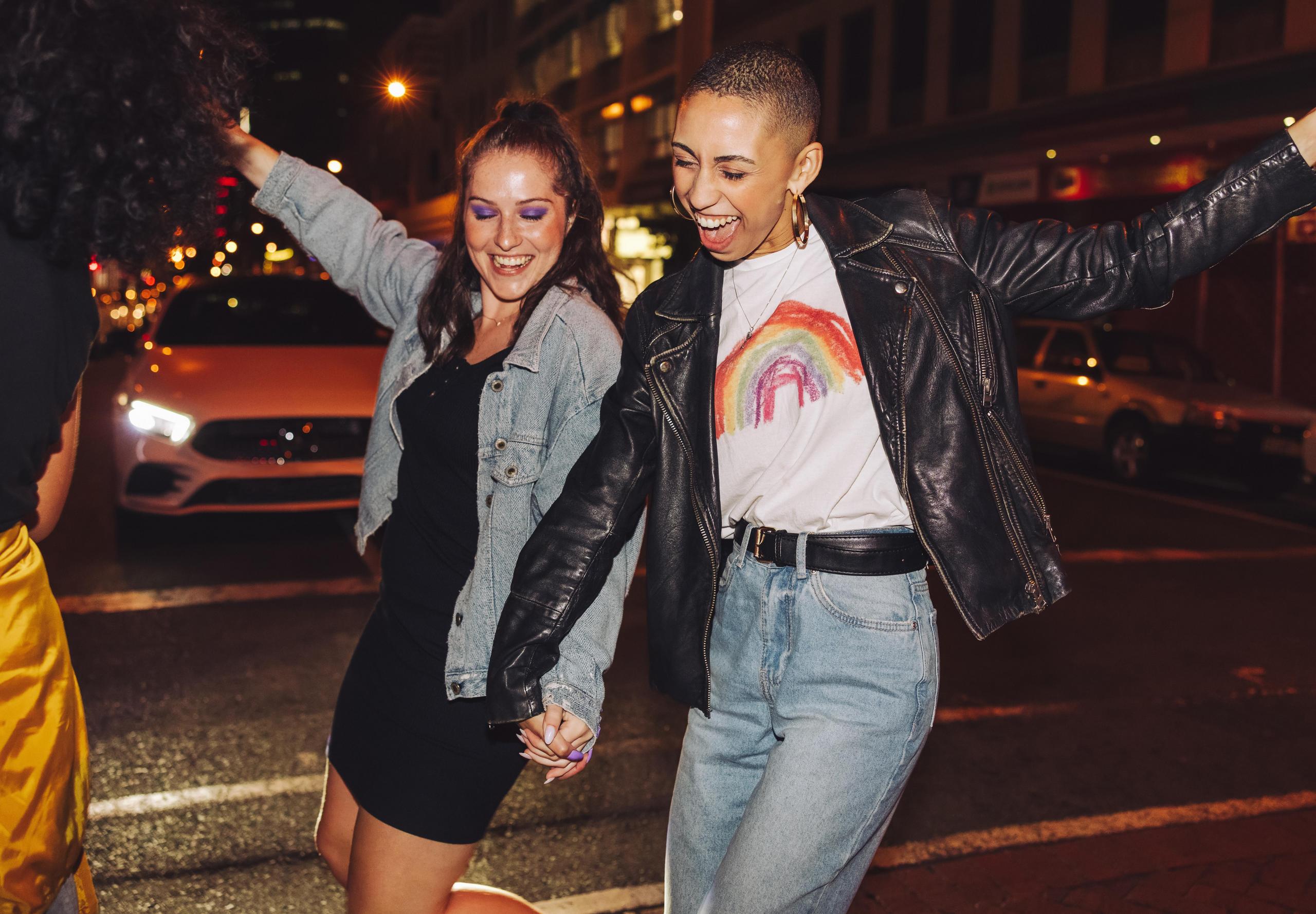 Zwei Jugendliche gehen bei Nacht lachend über eine Straße.