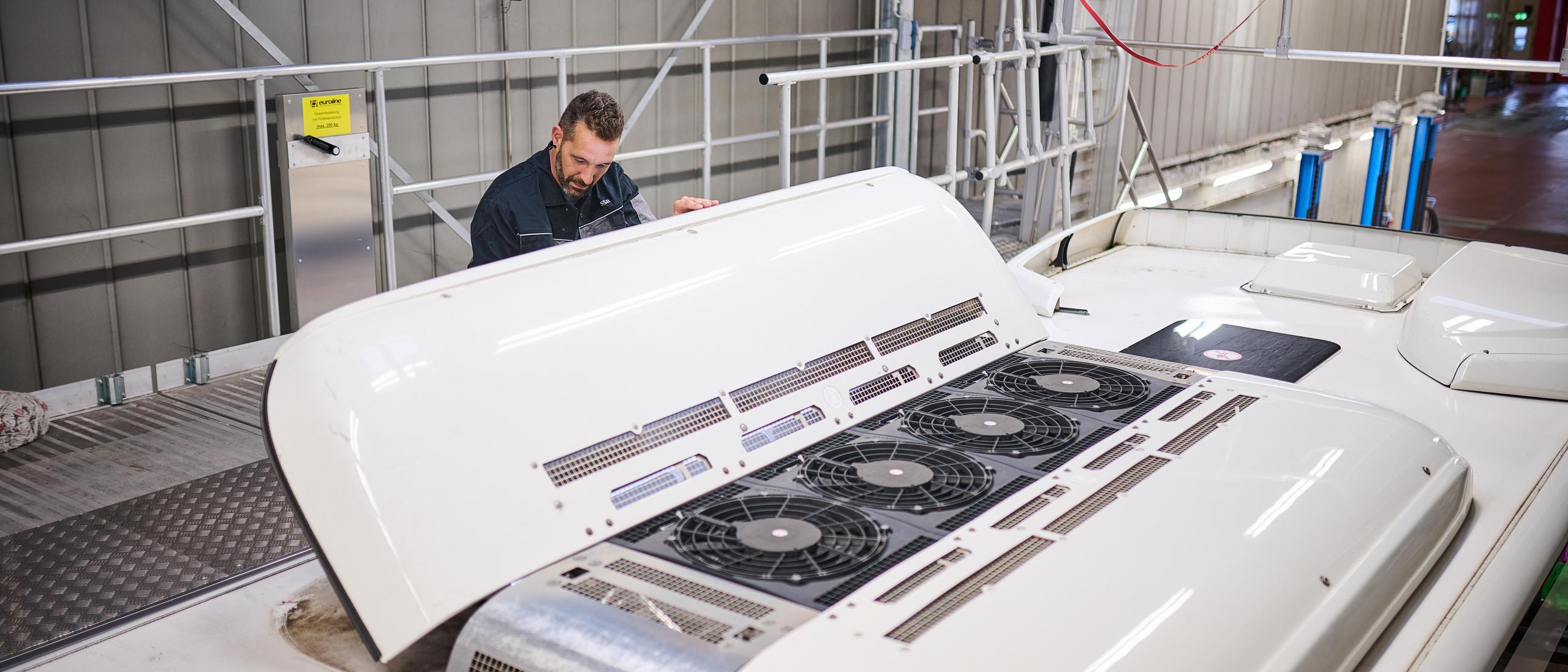 Ein Werkstattmitarbeiter prüft die Klimaanlage eines Busses.