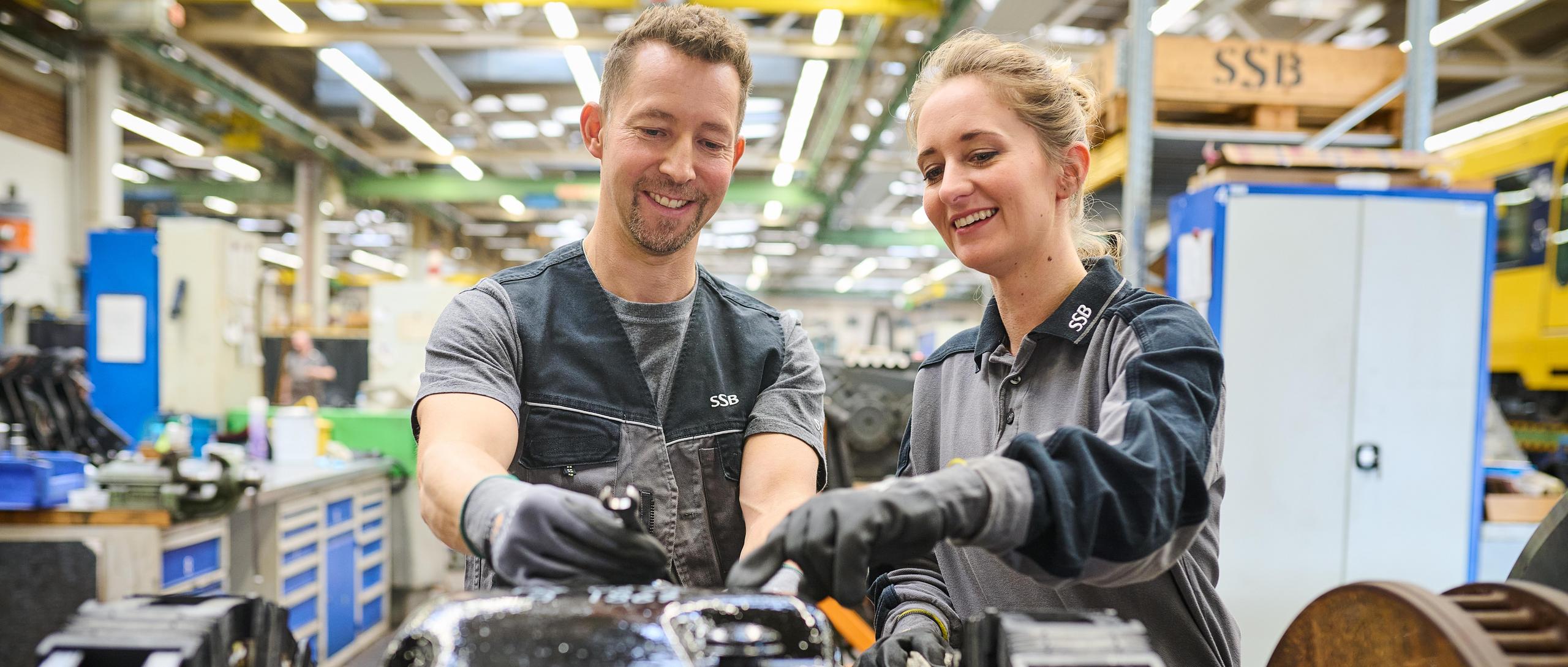 Zwei Werkstattmitarbeiter prüfen das Fahrgestell einer Stadtbahn.