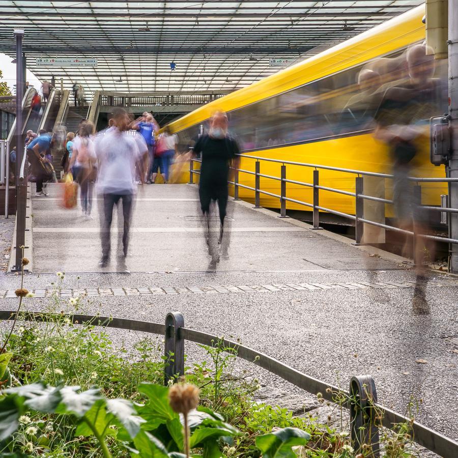 Fahrgäste bewegen sich auf einem Bahnsteig neben einer Stadtbahn.