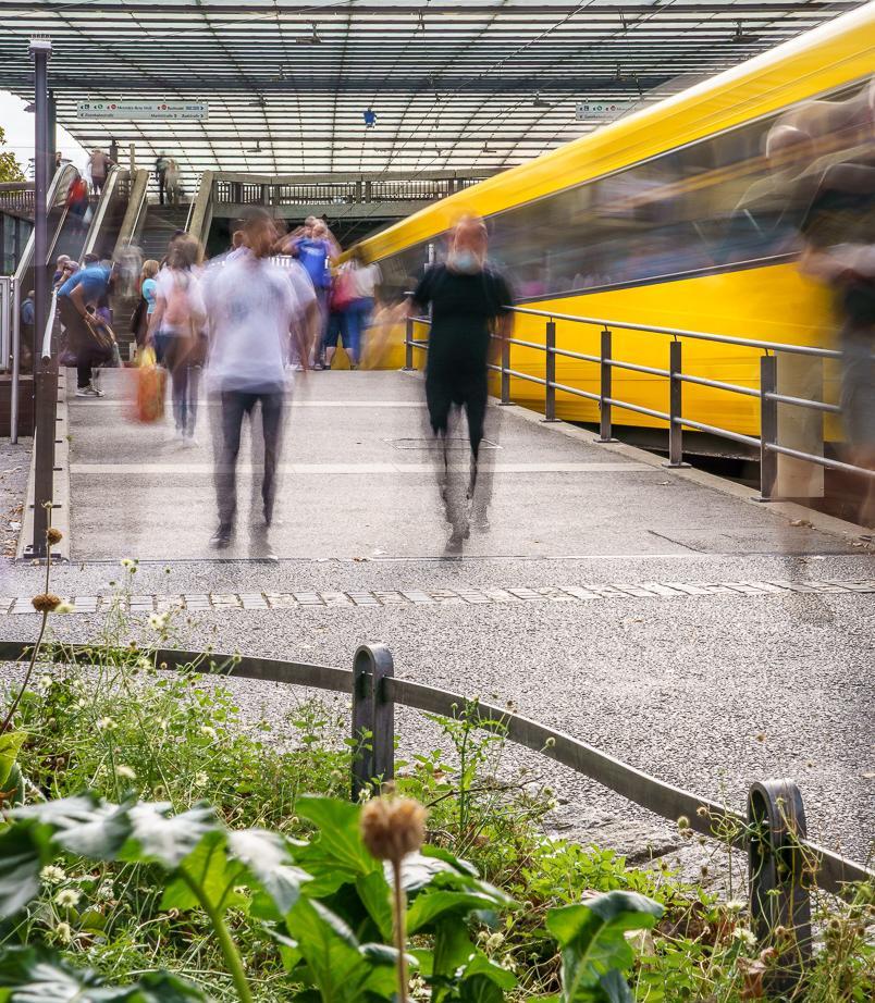 Fahrgäste bewegen sich auf einem Bahnsteig neben einer Stadtbahn.