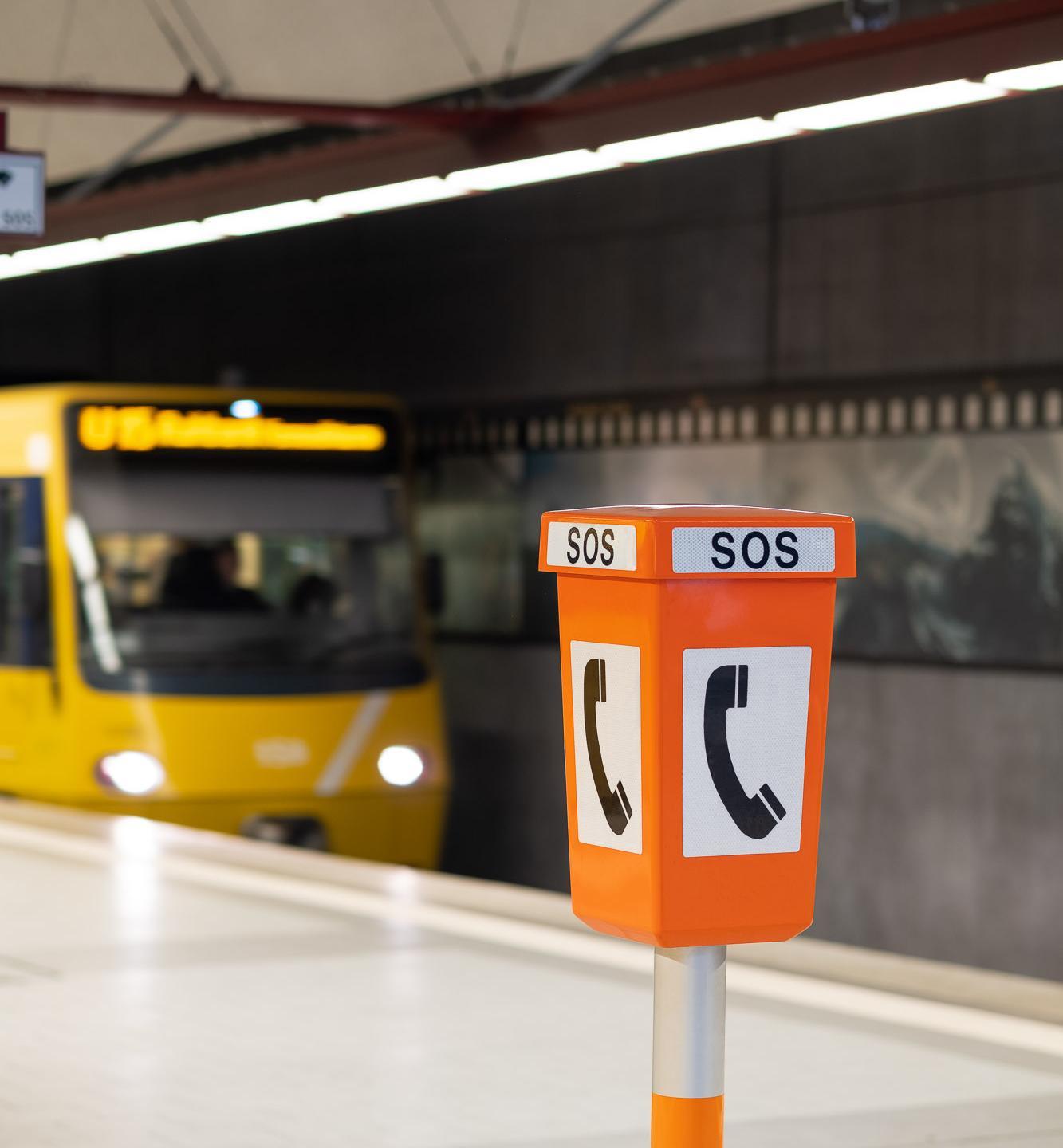 Notrufsprechstelle an einer Haltestelle mit fahrender Stadtbahn im Hintergrund