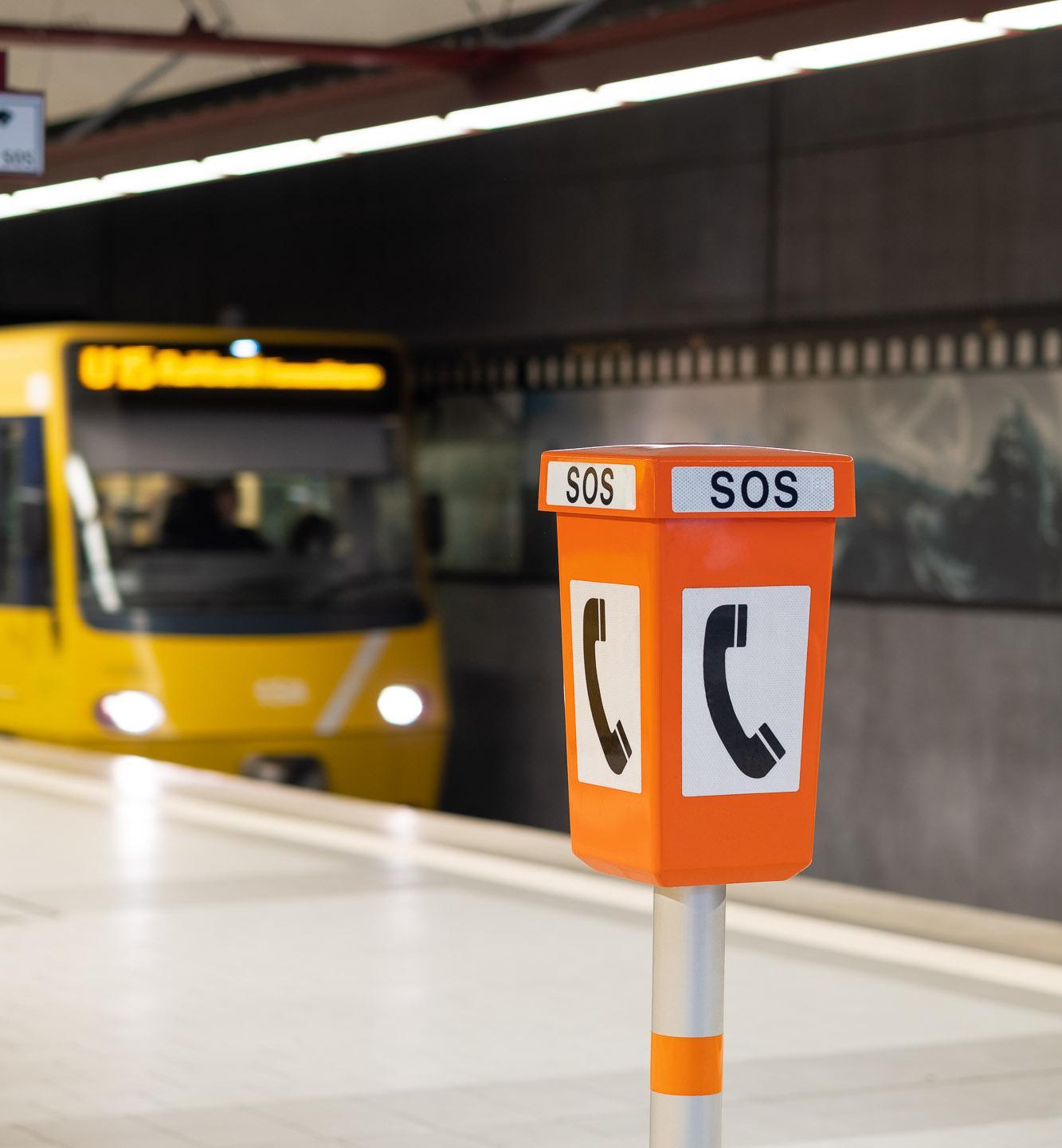 Notrufsprechstelle an einer Haltestelle mit fahrender Stadtbahn im Hintergrund