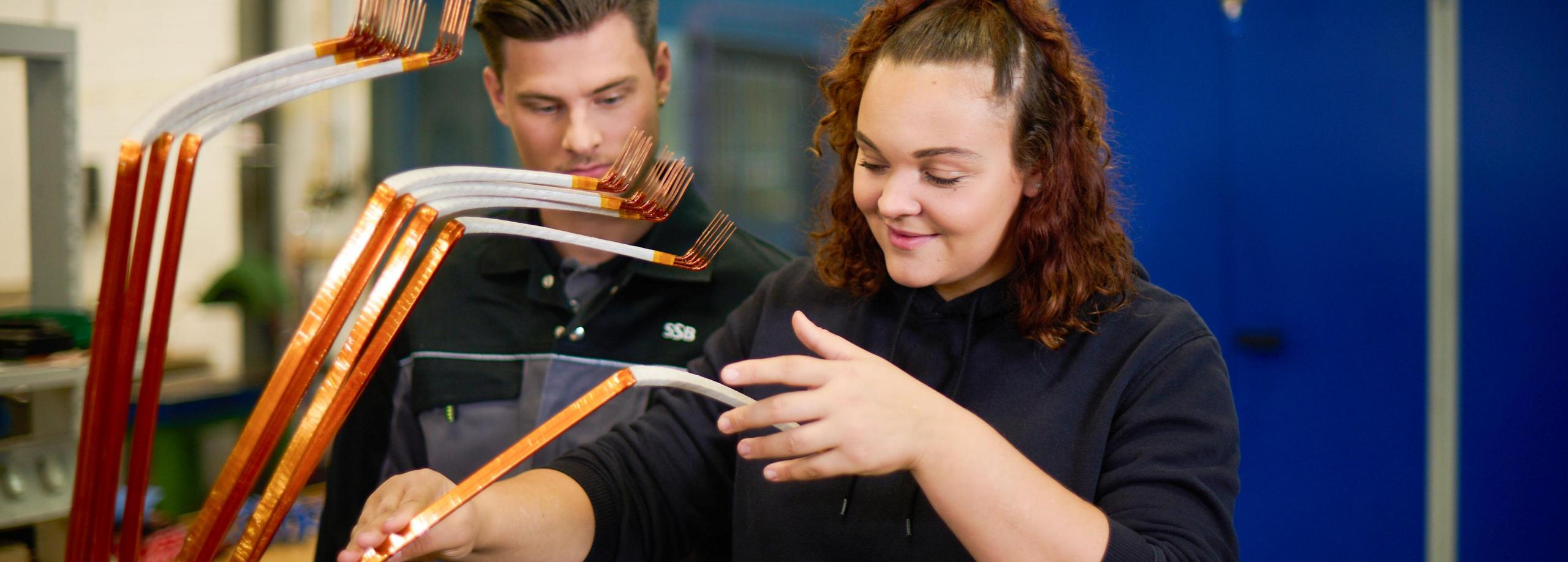 Zwei Auszubildende sichten in der Werkstatt einen Elektromotor.