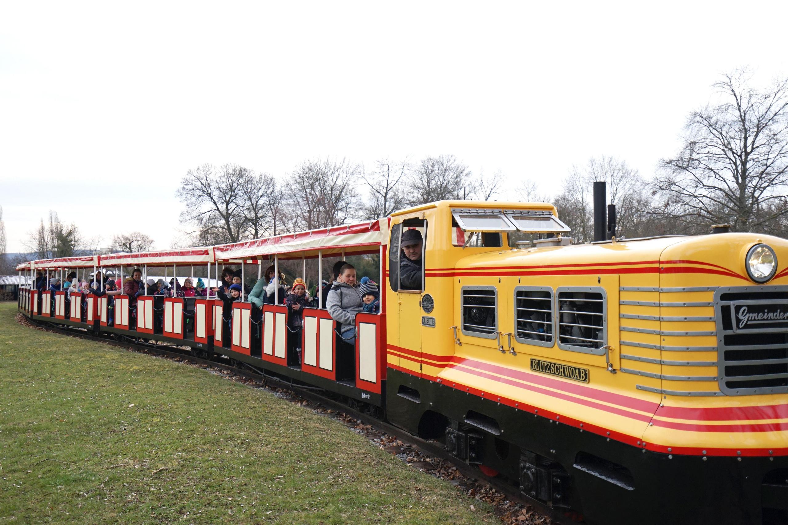 Eine Lokomotive fährt mit Fahrgästen durch den Killesbergpark.