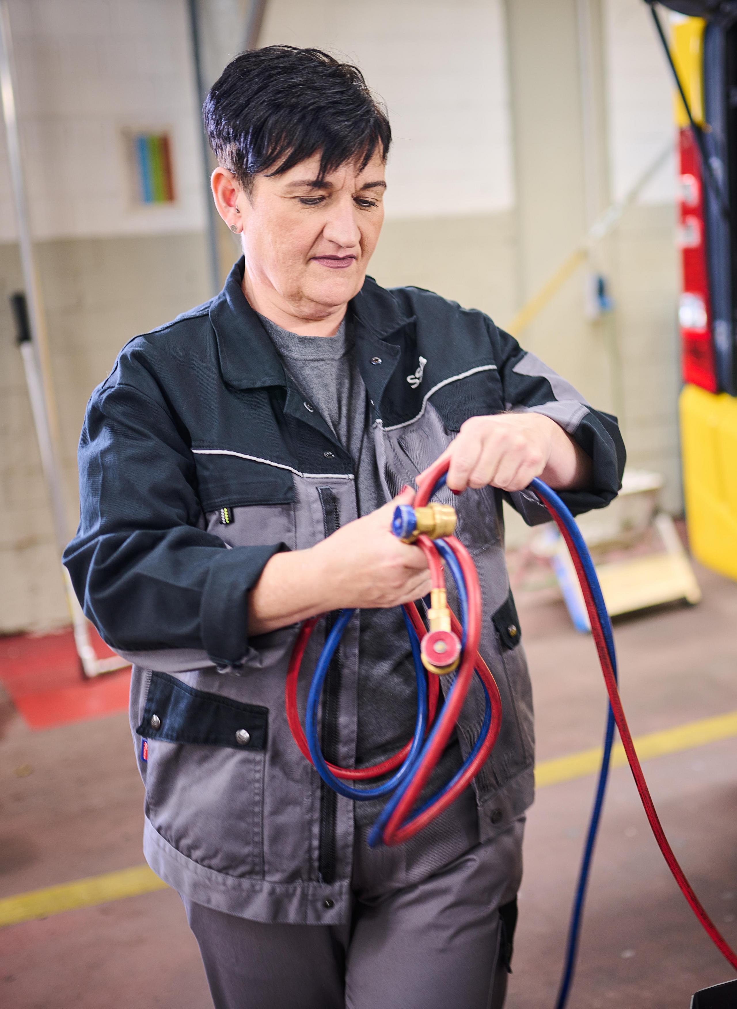 Eine Werkstattmitarbeiterin prüft Kabel.