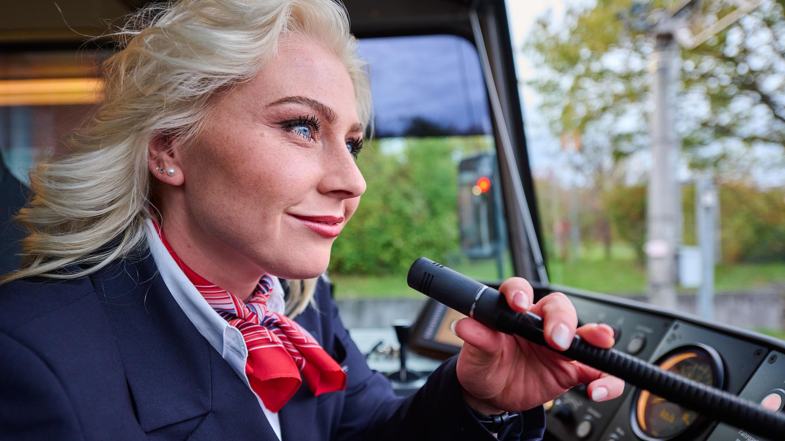 Eine Stadtbahnfahrerin spricht in ein Mikrofon im Fahrerstand der Stadtbahn.