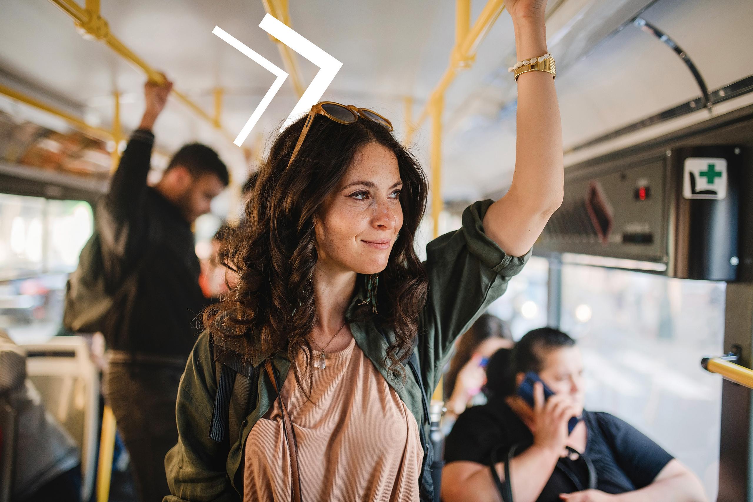 Eine Frau steht im Bus und schaut aus dem Fenster.