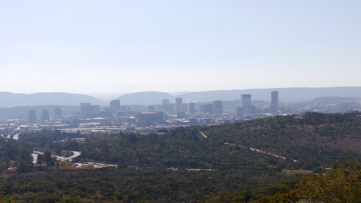Blick auf eine in der Ferne liegenden Großstadt mit Bergen im Hintergrund