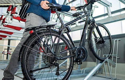 Person parkt ihr Fahrrad in einer Bike+Ride Vorrichtung