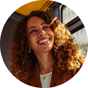 Portrait einer Frau mit lockige Haaren, die im Bus sitzt.