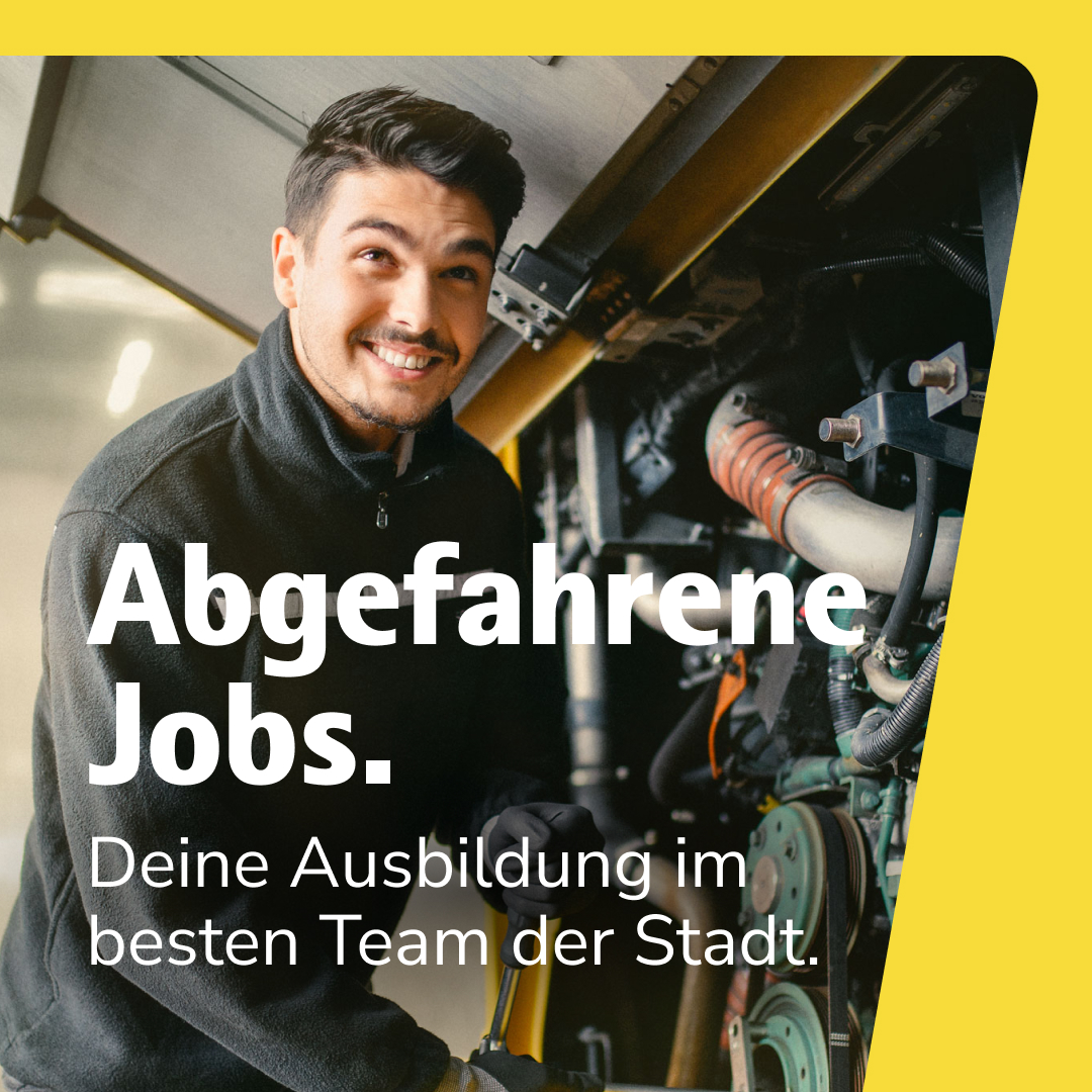 Ein junger Auszubildender arbeitet lächelnd am Busmotor.