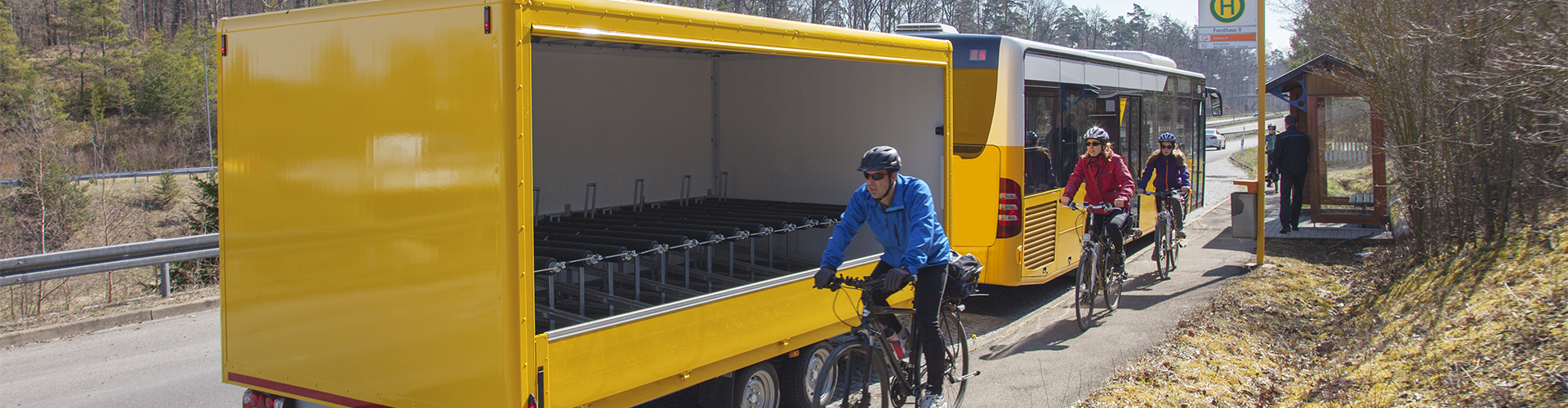 Fahrradfahrer fahren entlang eines Busses mit Rad-Tourer-Anhänger